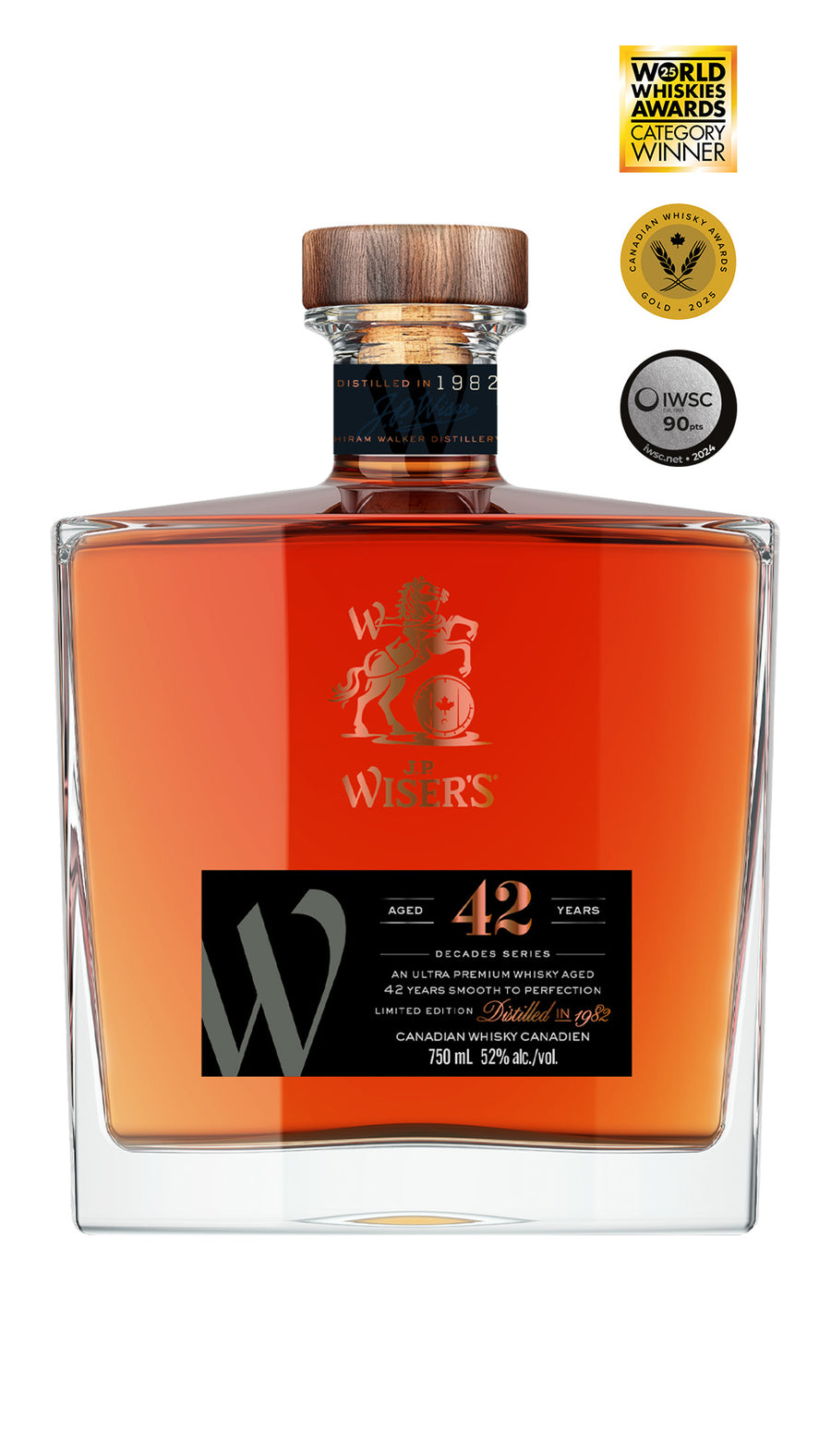 J.P. Wiser’s 42 Year Old Canadian Whisky 750ml bottle on a white background, featuring a clear glass bottle with a wooden cap and a luxurious black and gold-accented label. The label highlights the 42-year aging and Decade’s Series branding. The whisky inside has a dark golden hue. A rare, collectible Canadian whisky distilled in 1982, crafted in Ontario with rich vanilla, zesty citrus, and rye spice notes—celebrating the bold spirit of the 1980s.